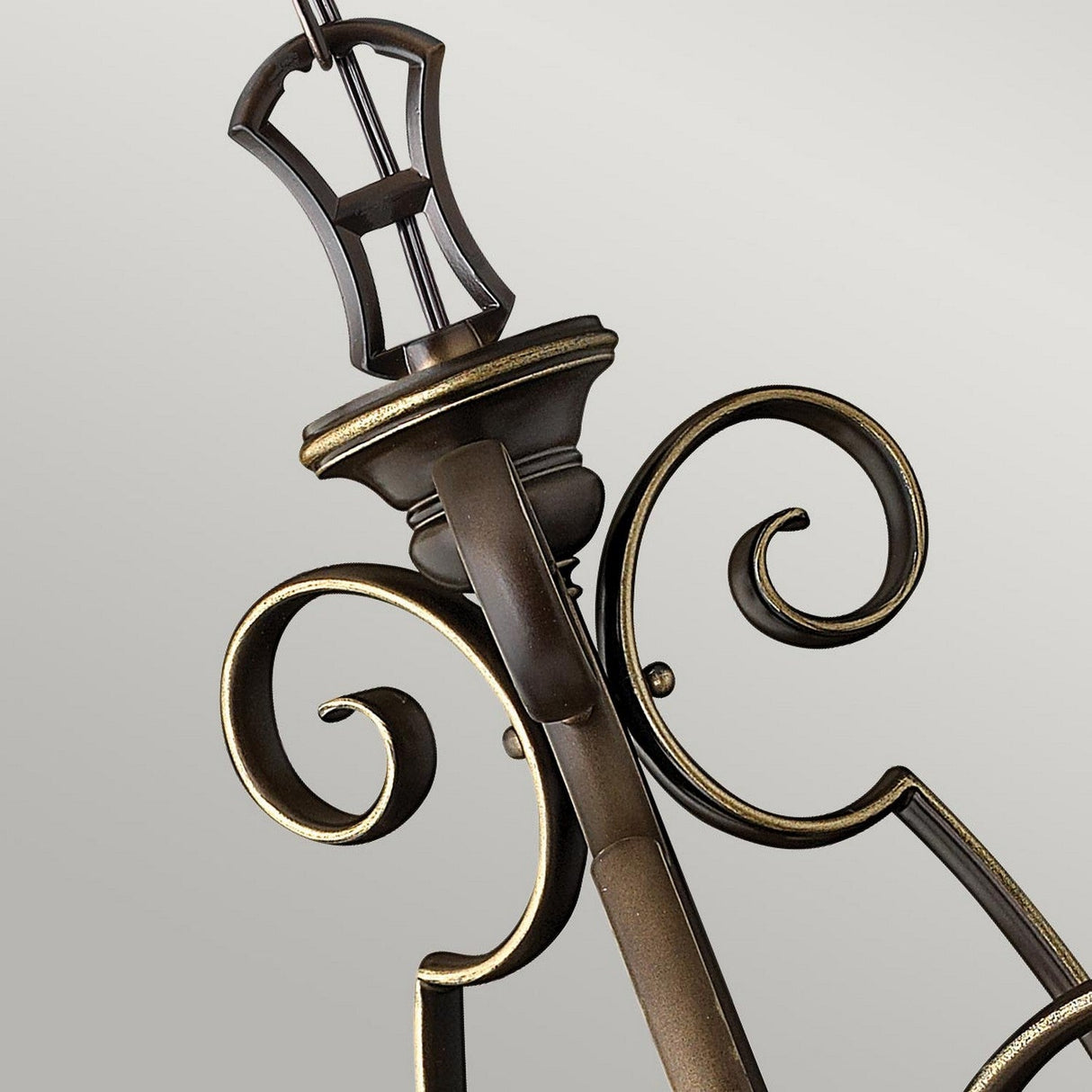 Close-up of an intricately designed arm of the Cello 3 Light Chandelier - Antique Bronze, showcasing elegant scrollwork against a plain background. The antique bronze finish, enhanced with gold accents, highlights the curves and craftsmanship, making it a stunning addition to any setting.