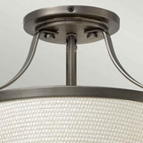 Close-up of the Charlotte 3 Light Semi Flush ceiling fixture, featuring a cream-colored linen shade with a woven texture and metal supports in antique nickel. The fixture is elegantly mounted on a light green ceiling.