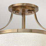 A close-up view of the Charlotte 3 Light Semi Flush fixture reveals its modern design. It boasts a brushed gold finish and features a woven linen shade. Elegant curved arms connect the shade to the base, offering a sleek and contemporary aesthetic against a neutral background.
