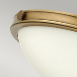 Close-up of the Collier 2 Light Small Flush fixture in Heritage Brass, showcasing a frosted glass dome and bronze-colored metal rim against a light gray background. This circular fixture encapsulates modern design.