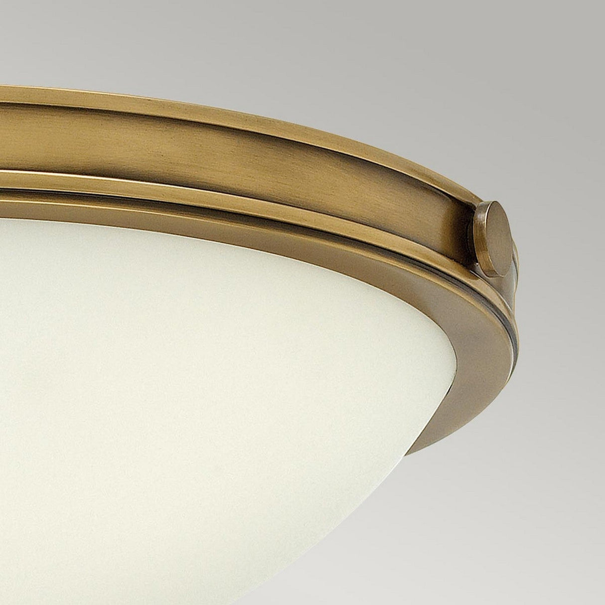 A close-up of the Collier 2 Light Small Flush - Heritage Brass, featuring a round, frosted glass shade with a heritage brass rim. The flush mount light is elegantly displayed against a light gray background.