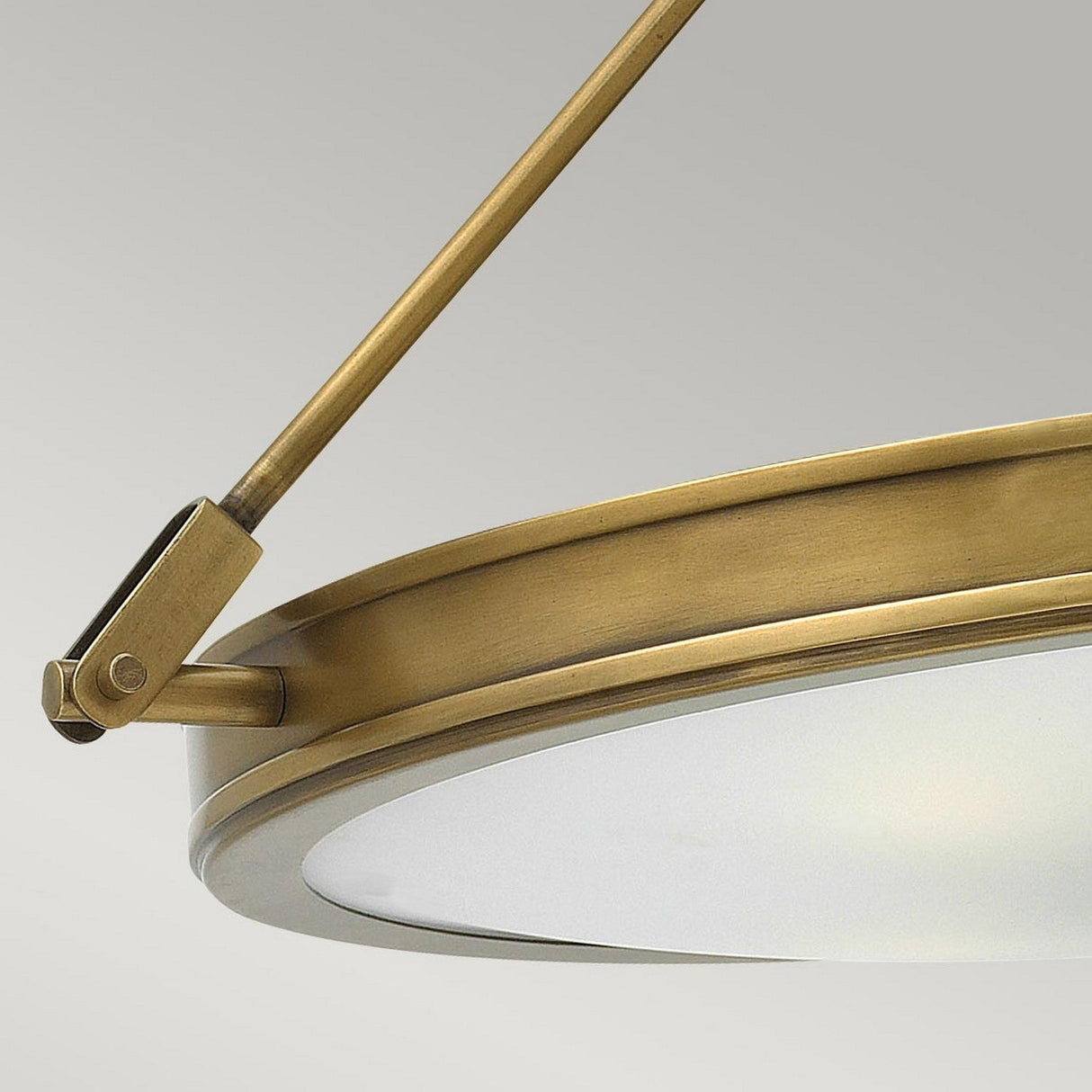 Close-up of the Collier 4 Light Large Semi Flush chandelier in heritage brass, showcasing its modern design with a frosted glass cover. A sturdy metal rod supports the fixture with an adjustable joint against a neutral gray background, highlighting its elegance.