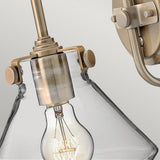 This close-up showcases the Congress 1 Light Clear Glass Wall Light in brushed caramel, highlighting an exposed bulb with a vintage design. Mounted on the wall with a decorative metal bracket, it emphasizes a minimalist yet elegant aesthetic while incorporating LED filament lamps for enhanced efficiency.