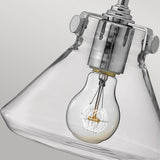 A close-up of the Congress 1 Light Clear Glass Wall Light - Chrome showcases a visible incandescent bulb within its clear, conical glass design. Set against a plain gray background, this vintage-style fixture features metallic accents and a chrome finish that highlight the bulb's filament.