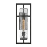The Cordillera 1 Light Outdoor Wall Light in black showcases a contemporary design with a rectangular metal frame that encases a cylindrical glass cover. Its visible filament bulb contributes to the industrial-chic aesthetic, while the bubble-like textured glass adds to its stylish charm.