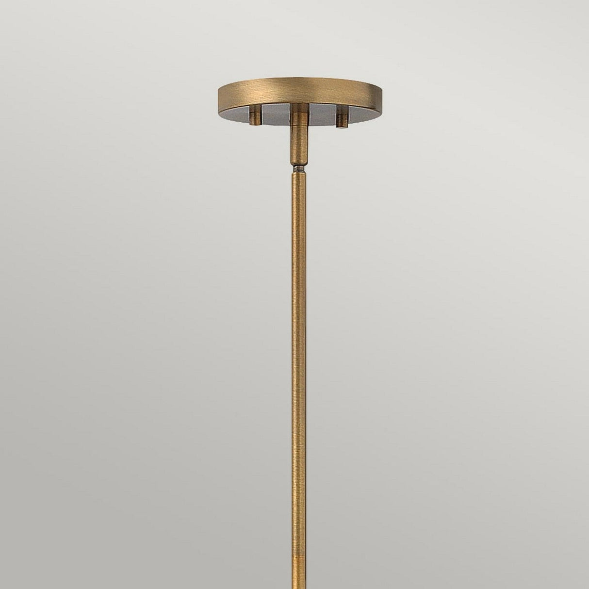 The Fulton 4 Light Pendant Chandelier in Bronze & Brass showcases a minimalist design with a round ceiling mount and long, slender rod, accented by a polished finish that adds an elegant touch.