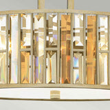 A close-up of the Gemma 3 Light Chandelier - Gold reveals vertical rectangular crystals in shades of gold and clear. These elegant crystals reflect light, creating a shimmering effect. The base of the fixture boasts a soft metallic hue, enhancing its luxurious appeal.