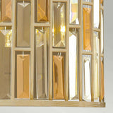 Close-up of the Gemma-1 2 Light Wall Light in gold, showcasing vertical rectangular glass prisms. These prisms, similar to amber pearl crystal, display shades of amber and clear as they reflect light within the gold finish frame.