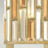 A close-up of the Gemma-2 2 Light Wall Light - Gold features a decorative fixture with rectangular, vertically arranged gold and clear glass prisms set in a gold frame. These prisms reflect and refract light, producing a shimmering effect characteristic of contemporary lighting designs.