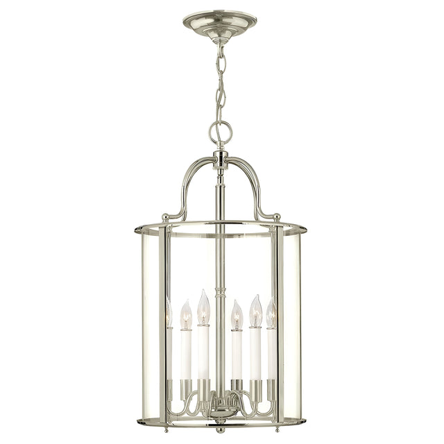 The Gentry 6 Light Large Pendant - Polished Nickel is a modern chandelier featuring clear bent glass panels. Its sleek design, complete with six candle-style bulbs elegantly suspended from a chain, adds a touch of sophistication to dining or living spaces.