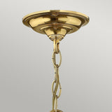 The Gentry 3 Light Small Pendant in Polished Brass showcases a classic and elegant appearance with its traditional lighting charm. A decorative chain hangs from the round base, mounted on a light-colored ceiling, highlighting its polished brass finish.