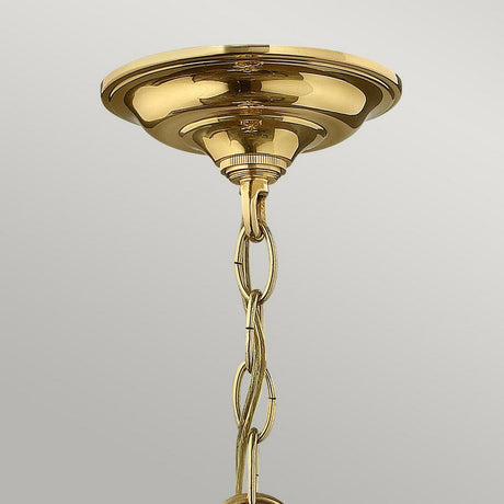 The Gentry 3 Light Small Pendant in Polished Brass showcases a classic and elegant appearance with its traditional lighting charm. A decorative chain hangs from the round base, mounted on a light-colored ceiling, highlighting its polished brass finish.