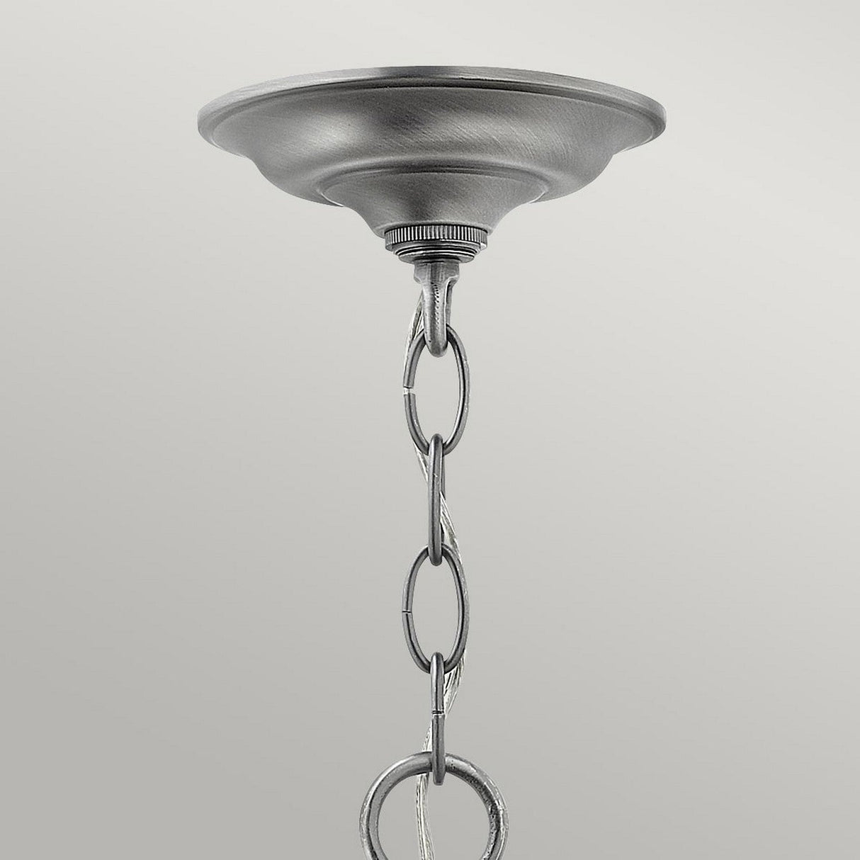 A close-up of the Gentry 3 Light Small Pendant - Silver features a decorative mounting plate and striking silver finish. The chain, adorned with interlocking oval links, elegantly extends downward. With clear bent glass panels, this pendant stands out against a simple light gray background.
