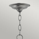 A close-up of the Gentry 3 Light Small Pendant - Silver features a decorative mounting plate and striking silver finish. The chain, adorned with interlocking oval links, elegantly extends downward. With clear bent glass panels, this pendant stands out against a simple light gray background.