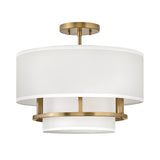The Graham 3 Light Duo-Mount Pendant/Semi-Flush - Lacquered Brass is a modern ceiling fixture featuring a cylindrical white fabric shade complemented by lacquered brass accents and a brass ceiling mount. Its sophisticated design combines contemporary aesthetics with dual-mount capability, offering versatile installation options.