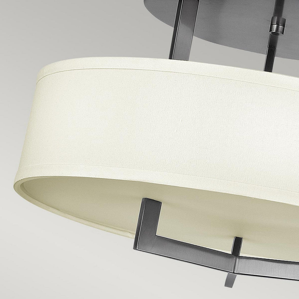 Close-up of the Hampton 3 Light Semi Flush in Antique Nickel, showcasing a modern ceiling light fixture with an ivory shade reminiscent of linen drum shades, complemented by sleek metal supports against a light gray background.