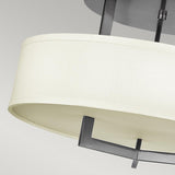 Close-up of the Hampton 3 Light Semi Flush in Antique Nickel, showcasing a modern ceiling light fixture with an ivory shade reminiscent of linen drum shades, complemented by sleek metal supports against a light gray background.