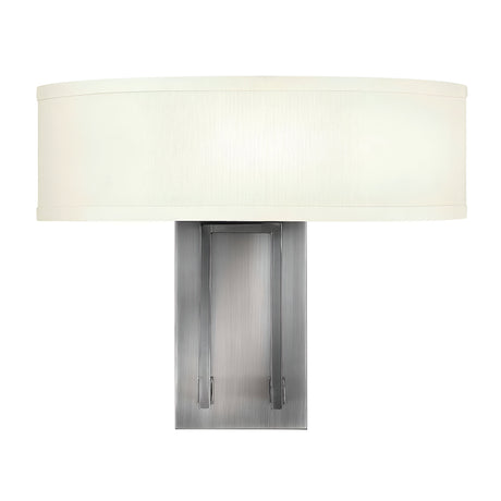 The Hampton 2 Light Wall Light - Antique Nickel With Ivory Shade features a contemporary design, incorporating an antique nickel rectangular base with a large, horizontally oriented off-white linen drum shade. It provides a soft, diffused glow suitable for any modern environment.