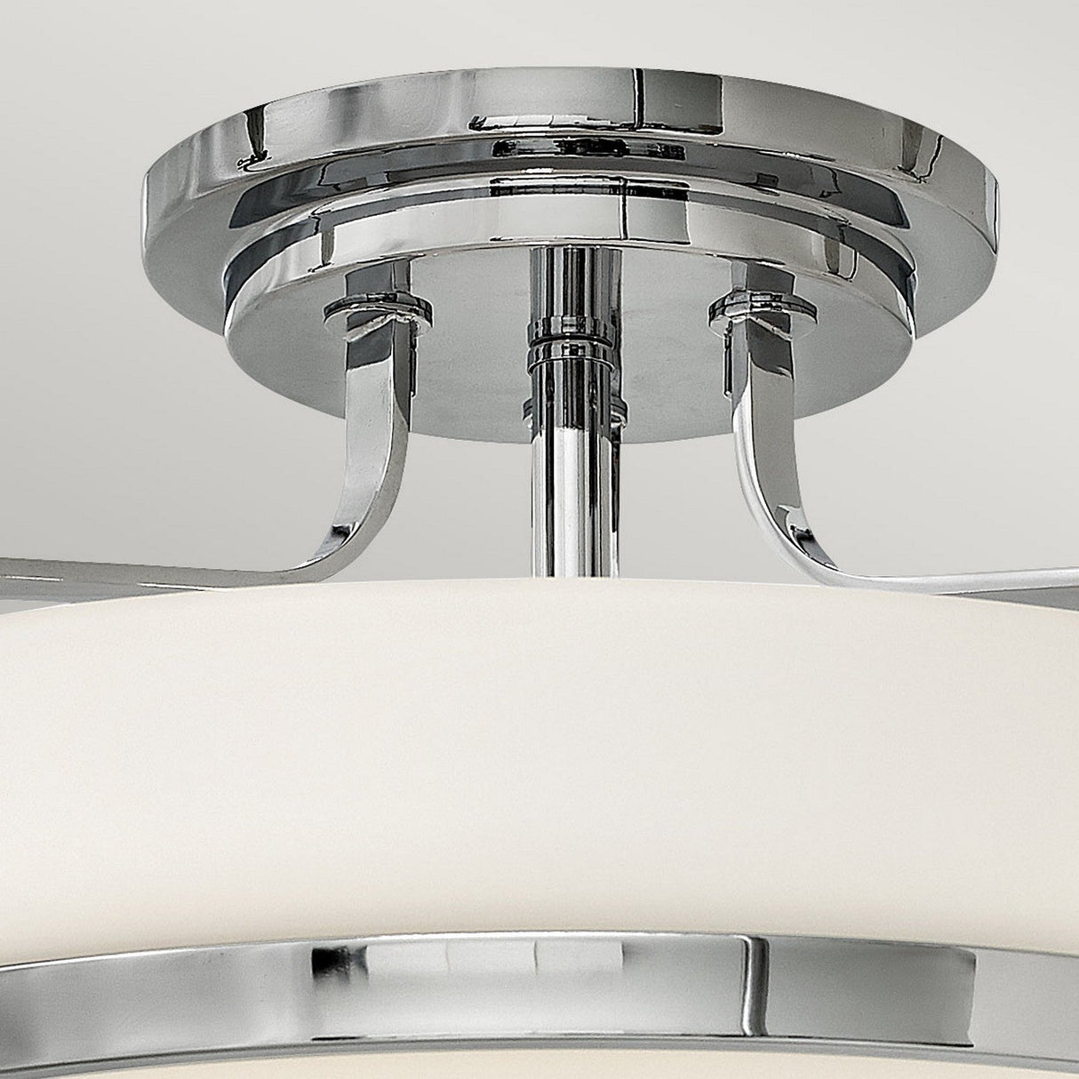 A close-up of the Harper 3 Light Medium Semi Flush ceiling light fixture, featuring a polished chrome finish and opal etched glass shade. The sleek metal components connect to the ceiling mount, highlighting its contemporary design that exudes elegance and style.