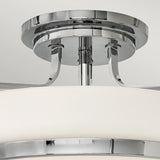 A close-up of the Harper 3 Light Medium Semi Flush ceiling light fixture, featuring a polished chrome finish and opal etched glass shade. The sleek metal components connect to the ceiling mount, highlighting its contemporary design that exudes elegance and style.