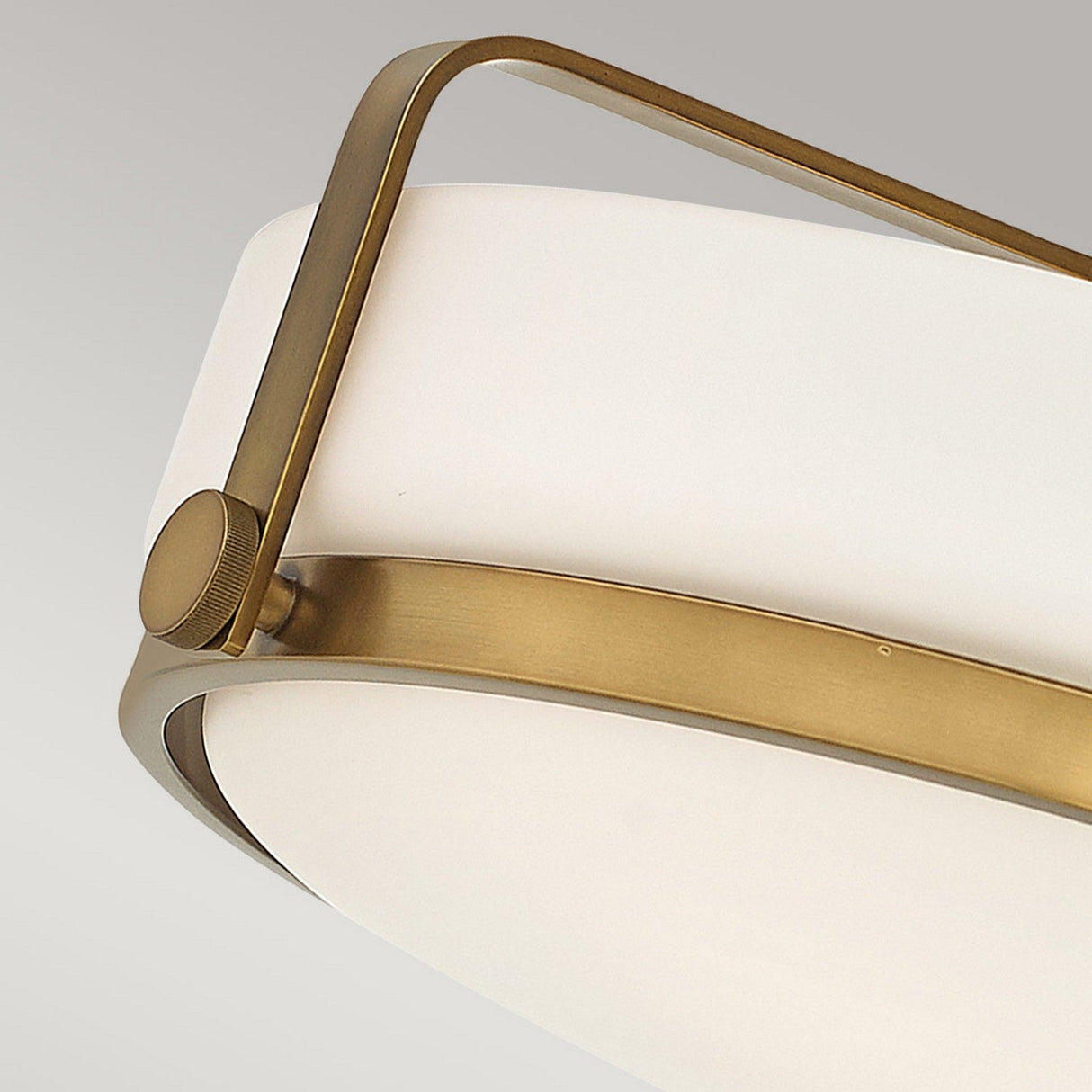 A close-up of the Harper 3 Light Medium Semi Flush showcases its modern design, featuring a white, rounded opal etched glass shade encased in a sleek heritage brass frame. The minimalist style exudes elegance, with a soft glow radiating through the translucent material.