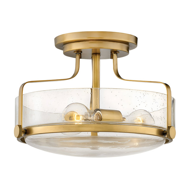 The Harper 3 Light Small Semi Flush in Heritage Brass features two exposed bulbs and a clear seeded glass shade with subtle speckles, mounted on a short brass stem.