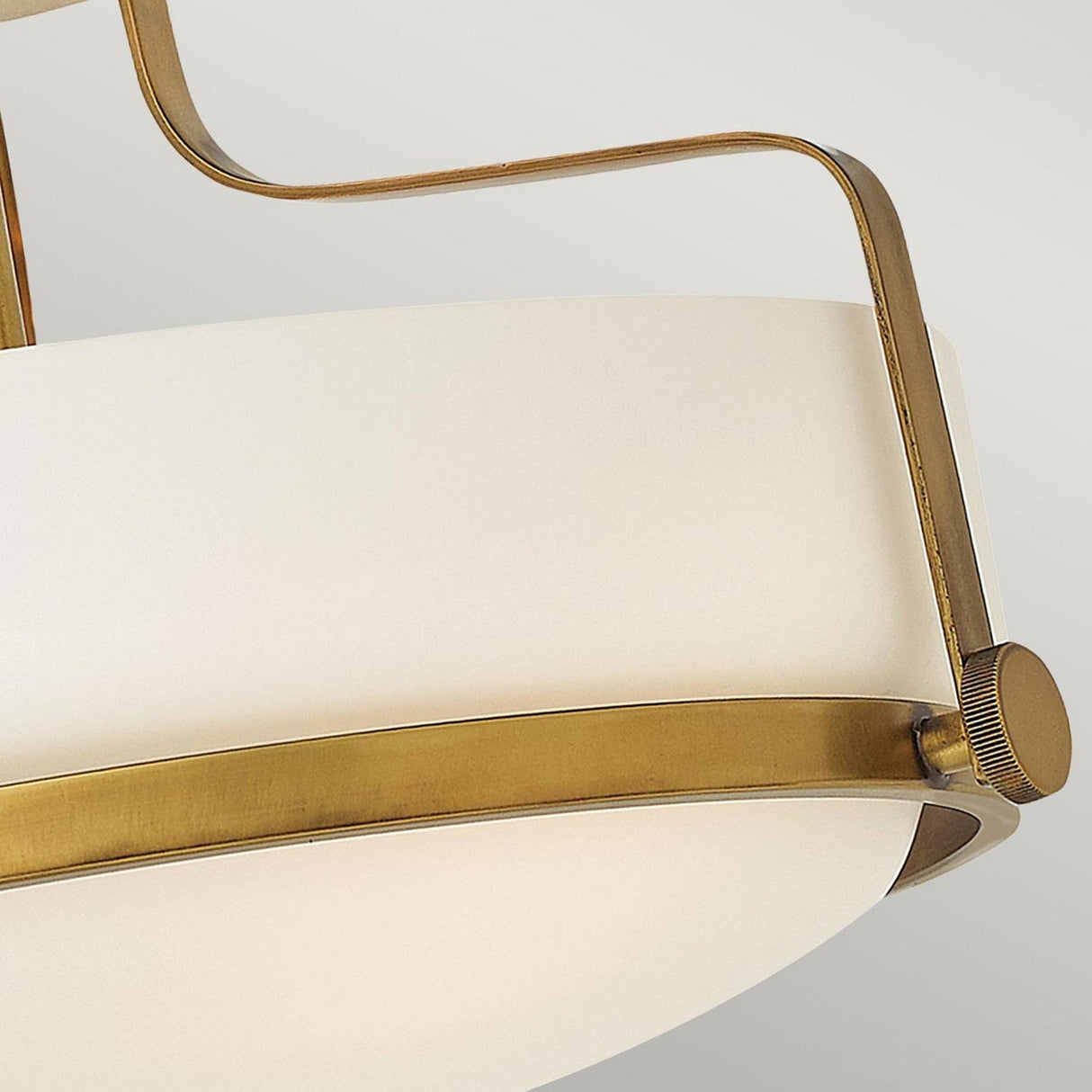 Here's a close-up view of the Harper 3 Light Small Semi Flush, featuring a circular white shade made from opal etched glass encased in a heritage brass frame. The design showcases a semi flush mount with a sleek metal arm, highlighting its minimalist aesthetic against a neutral background.