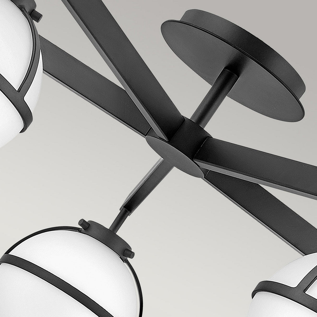 Close-up of the Hollis 5 Light Semi Flush, showcasing a black finish with contemporary metal arms and round opal etched glass shades. Its geometric design contrasts elegantly against the neutral background.