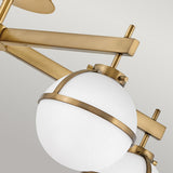 Close-up of the Hollis 5 Light Semi Flush in heritage brass, highlighting its opal etched glass lampshades. The design exhibits intersecting rods and an elegant, minimalist aesthetic set against a light gray background.
