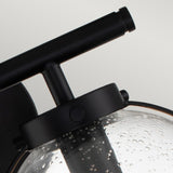 A close-up of the Hollis 2 Light Wall Light showcases its modern black finish paired with clear glass. The sleek, minimalist design is enhanced by the decorative bubble-textured surface, subtly echoing Art Deco lighting aesthetics.