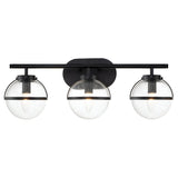 The Hollis 3 Light Wall Light - Black With Clear Glass showcases a contemporary Art Deco design with three spherical glass shades, each characterized by a speckled texture, mounted on a sleek black metal bar. This stylish fixture houses glowing bulbs that add elegance to any room's décor and is designed for easy wall installation.