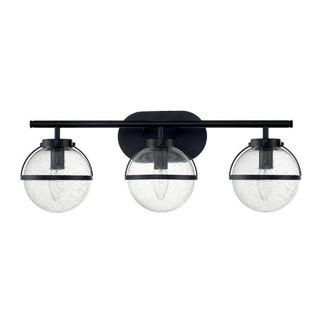 The Hollis 3 Light Wall Light in black with clear glass showcases a contemporary Art Deco style. It features three globe lampshades made of clear glass, mounted on a horizontal black bar. Each globe encases a filament bulb that highlights its sleek and elegant design.