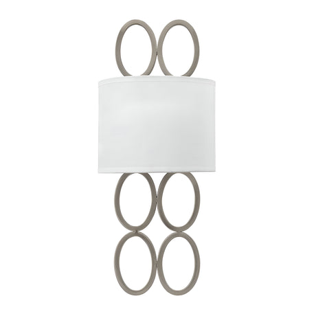 The Jules 2 Light Wall Light - Brushed Nickel boasts a sleek design with a modern white rectangular shade, adorned with an elegant vertical arrangement of six interconnected metallic oval rings, three placed above and three below, adding a sophisticated touch to any room.