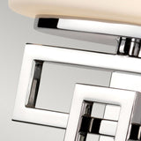 Close-up of the Lanza 1 Light Wall Light, showcasing contemporary craftsmanship with interlocking silver squares and a frosted glass element on top. The design features a sleek, polished chrome finish set against a soft gray background.