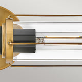 The Masthead 2 Light Wall Light, featuring a cylindrical clear glass shade and exposed LED filament, is showcased in detail. It's adorned with Heritage Brass finish accents alongside black elements, combining sleek, minimalist design with a touch of nautical elegance against a neutral setting.