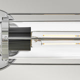 Close-up of the Masthead 2 Light Wall Light - Polished Chrome & Black, showcasing a cylindrical glass shade. The fixture offers a touch of nautical charm with its polished chrome accents and visible LED filaments, set against a plain gray background.