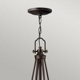 The Mayflower 6 Light Chandelier - Bronze gracefully hangs from the ceiling with its chain suspension, featuring a minimalist modern design. Its polished bronze finish harmonizes with the neutral backdrop, and the etched amber glass shades bring warmth to this exquisite chandelier.