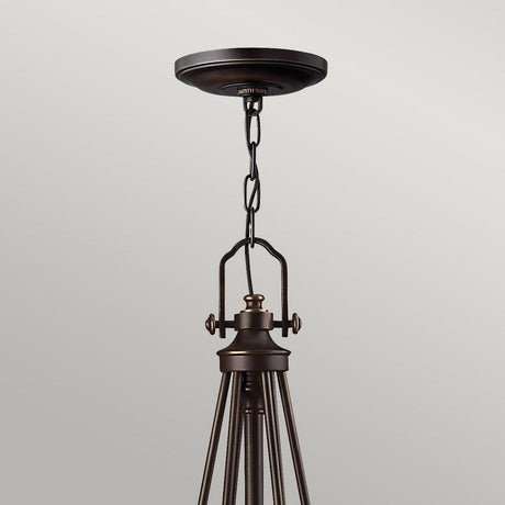 The Mayflower 6 Light Chandelier - Bronze gracefully hangs from the ceiling with its chain suspension, featuring a minimalist modern design. Its polished bronze finish harmonizes with the neutral backdrop, and the etched amber glass shades bring warmth to this exquisite chandelier.