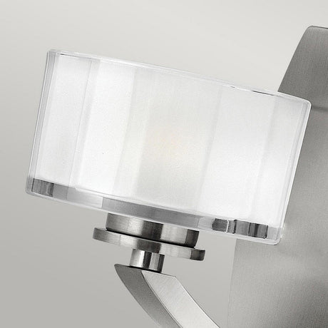 A contemporary wall light fixture, the Meridian 1 Light Wall Light - Brushed Nickel features a faceted glass shade and a brushed nickel base with clean, sleek lines for a modern aesthetic.