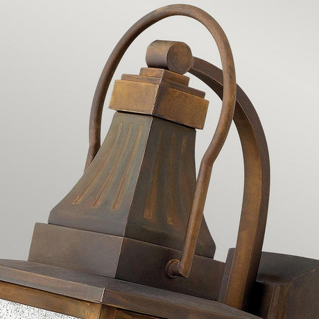 Close-up of the Montauk 2 Light Small Wall Lantern - Sienna. This lantern, made from solid brass, showcases a fluted top and curved handle, offering a classic and robust design against a neutral backdrop.