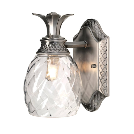The Plantation Outdoor 1 Light Wall Light in polished antique nickel is a pineapple-shaped optic glass fixture designed for wall mounting in outdoor settings. It features a textured glass globe and metal base, casting a warm glow through its intricate pattern.