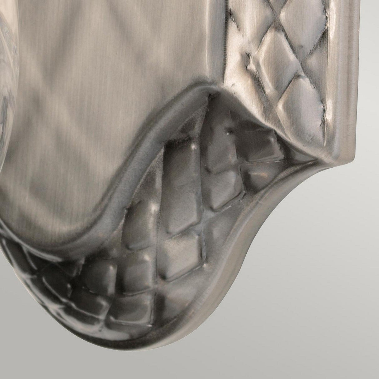 Close-up of the Plantation Outdoor 1 Light Wall Light in polished antique nickel, featuring a textured metallic surface with a curved edge and an embossed woven pattern along the border. The brushed finish gives the metal a soft sheen reminiscent of this elegant design.
