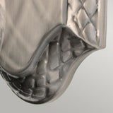 Close-up of the Plantation Outdoor 1 Light Wall Light in polished antique nickel, featuring a textured metallic surface with a curved edge and an embossed woven pattern along the border. The brushed finish gives the metal a soft sheen reminiscent of this elegant design.