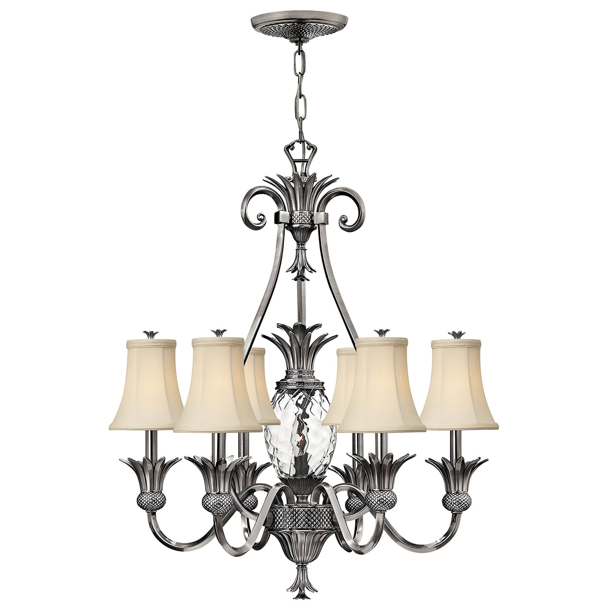 The Plantation 7 Light Chandelier in Polished Antique Nickel showcases six arms adorned with beige fabric lampshades and a central clear optic glass design shaped like a pineapple. Its detailed metalwork is elegantly suspended by a chain, making it perfect for sophisticated interior settings.