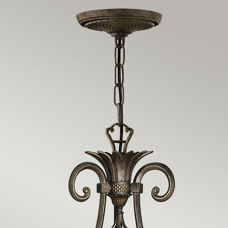 Close-up of the Plantation 7 Light Chandelier in Pearl Bronze, showcasing decorative metal curves, a textured chain, and pineapple-shaped clear optic glass details against a plain gray background.