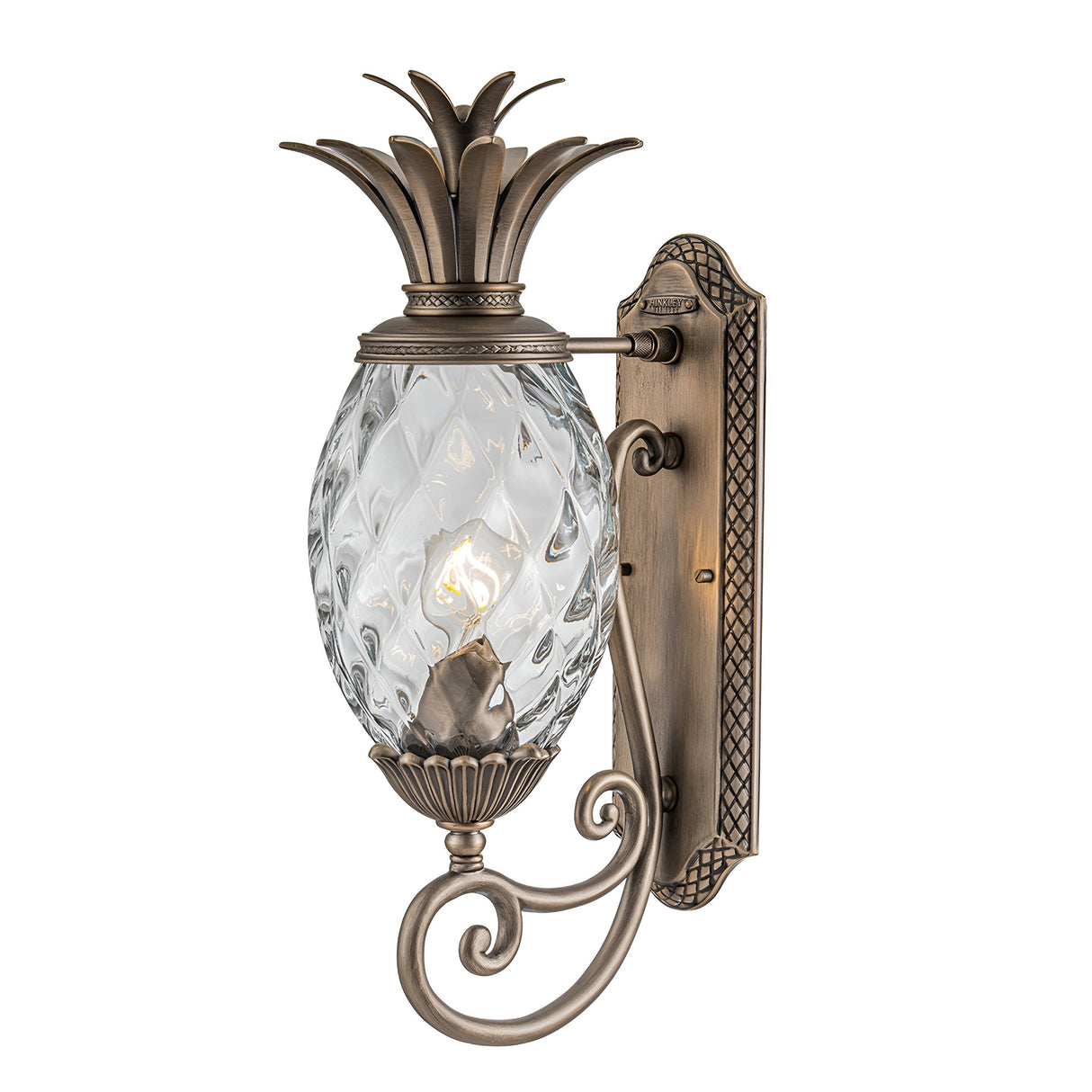 The Plantation Outdoor 1 Light Medium Wall Lantern features a decorative pineapple-shaped design and is wall-mounted. It has a burnished bronze finish, complemented by pineapple optic glass lamp housing and intricate detailing on the metal bracket and arm.