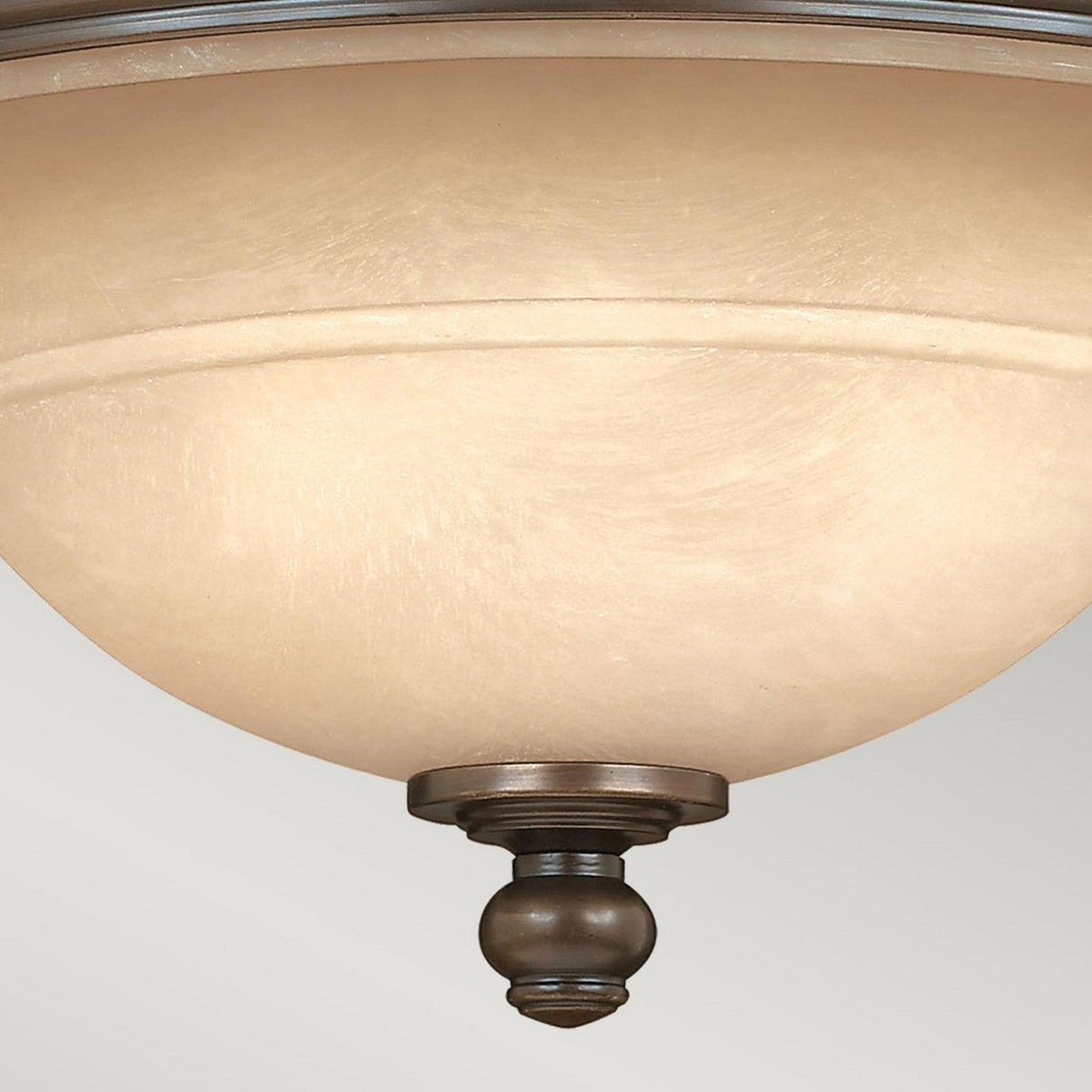 Close-up of a ceiling-mounted light fixture showcasing a frosted glass dome and an old bronze finish. Its design includes a central decorative finial at the base. The Plymouth 3 Wall Light - Bronze emits a soft, warm glow, enhanced by its elegant organza shades.