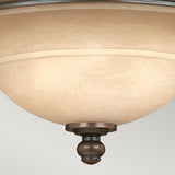 Close-up of a ceiling-mounted light fixture showcasing a frosted glass dome and an old bronze finish. Its design includes a central decorative finial at the base. The Plymouth 3 Wall Light - Bronze emits a soft, warm glow, enhanced by its elegant organza shades.