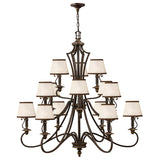 The Plymouth 15 Light Chandelier - Bronze is a grand, vintage-inspired piece featuring multiple tiers with cream-colored lampshades and an elegant bronze metal frame with curving arms. This stunning chandelier hangs gracefully from a chain, bringing timeless charm to any space.