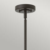 A close-up view of the Rigby 1 Light Pendant in bronze and brass, featuring a sleek cylindrical rod descending from a circular base. The industrial design of this fixture pops against a gradient background of light gray.